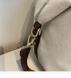 Detailed close-up of premium gold-tone metal hardware on a beige woven canvas bag