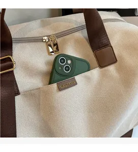 Detail of canvas tote bag with front pocket showing smartphone storage and durable handles