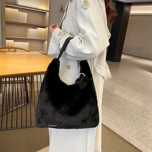 Detail of black faux fur tote bag with purple woven label and plush pom-pom charm