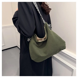 Dettaglio borsa hobo in velluto verde scuro con tracolla intrecciata su blazer nero