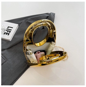 Detail view of oval gold mirror evening bag showing interior capacity and chain strap