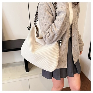 Dettaglio della trama a maglia e della tracolla a righe sulla grande borsa hobo tote