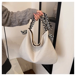 Dettaglio della borsa tote in tela a righe beige con manici in corda intrecciata bicolore