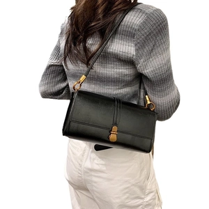 Chic black rectangular underarm bag with gold hardware shown on a model's shoulder