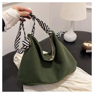 Dettaglio della borsa tote in velluto a coste verde scuro con tracolle intrecciate bicolore