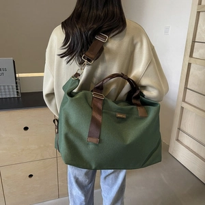 Detail of dark green canvas travel bag with brown nylon straps and bronze hardware