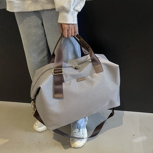 Detail of large travel duffel bag showing reinforced wide handles and durable grey fabric