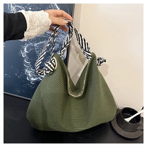 Dettaglio borsa in maglia verde militare con manico intrecciato a righe bianche e nere