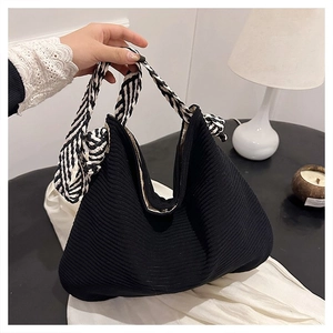 Dettaglio della borsa tote in maglia a pieghe nera con manici in corda intrecciata