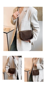 Detail view of a dark brown matte saddle bag with a golden zipper and thin strap