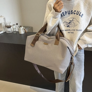 Close-up of grey high-density fabric travel bag with brown nylon straps and metal logo