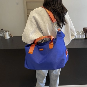 Detail of navy canvas crossbody bag featuring contrasting orange straps and spacious interior