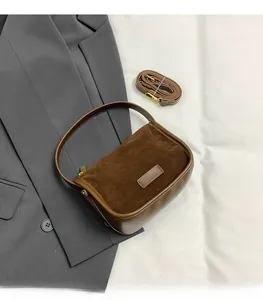 Close-up of brown suede and leather patchwork handbag with gold hardware details