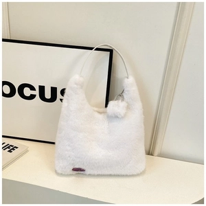 Minimalist white plush tote bag with pom-pom pendant on a stylish modern studio background
