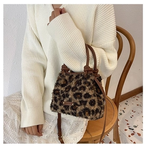 Détail d'un sac seau en peluche léopard avec poignées en cuir et logo métallique