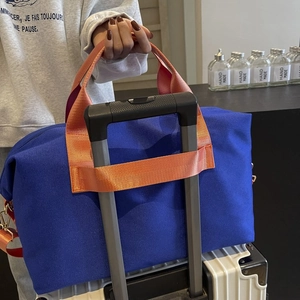 Detail of travel duffle bag with orange trolley sleeve secured to luggage handle