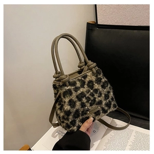 Détail du sac en peluche léopard avec poignée en cuir nouée et plaque logo en métal