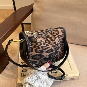 Leopard print PU leather crossbody bag with gold zipper displayed on a book