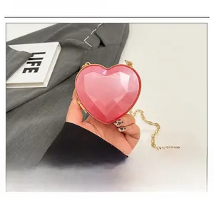 Detail view of heart-shaped pink acrylic handbag with geometric facets and gold chain