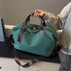 Detail of green canvas travel bag with brown nylon handles and adjustable shoulder strap