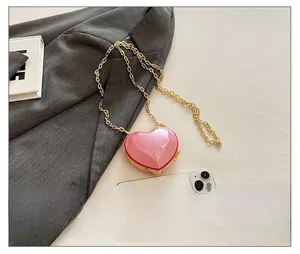 Pink heart-shaped acrylic mini bag size comparison with a smartphone on a suit background