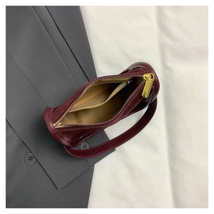 Detail of burgundy leather handbag showing interior lining and gold zipper closure