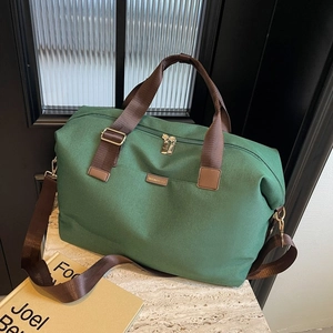 Detail of dark green travel tote featuring sturdy brown handles and golden metal zippers