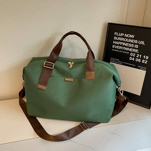 Close-up of forest green canvas travel bag with brown handles and golden metal zipper