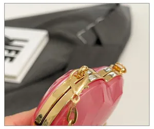 Close-up of pink heart-shaped bag showing gold metal hardware and glossy quilted texture
