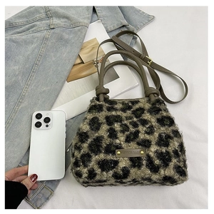 Détail du sac en peluche léopard avec poignées en cuir et plaque logo tendance