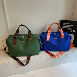 Detail view of large capacity canvas duffel bags in green and blue on marble steps