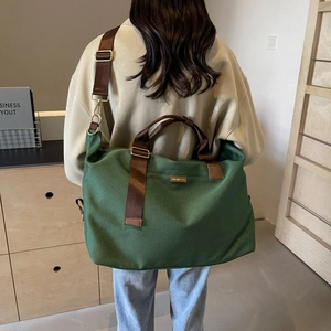 Detailed back view of a model wearing a large dark green canvas shoulder bag