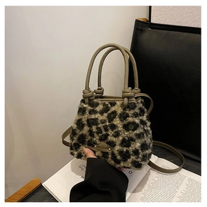 Détail d'un sac en peluche léopard avec poignées en cuir vert et plaque logo métallique