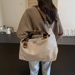 Detailed view of large grey canvas tote bag with brown nylon straps in a cafe setting