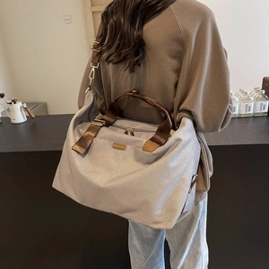 Outdoor canvas travel bag in grey and brown worn by a model in a modern interior