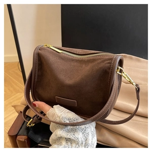 Detail of a brown suede half-moon shoulder bag with golden zipper and leather trim