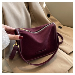 Close-up of burgundy suede shoulder bag with gold hardware and smooth leather trim