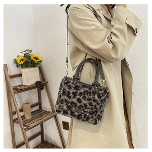 Détail du sac bandoulière en fausse fourrure léopard avec poignées en cuir et accents dorés