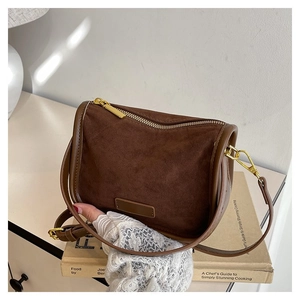 Detail of dark brown suede crossbody bag with premium stitching and gold hardware