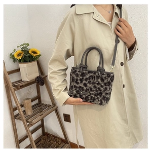 Détail du sac bandoulière en fausse fourrure léopard avec poignées en cuir sur un manteau
