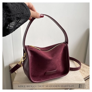 Detail of burgundy PU leather crossbody bag with suede-like panels and gold metal hardware