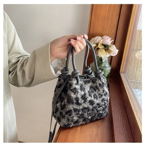 Détail du sac en peluche léopard avec poignée en cuir gris et design à nœuds