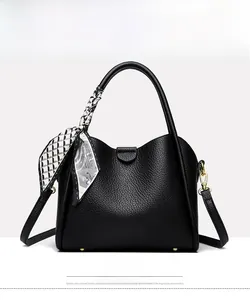 Front view of black pebble leather handbag with decorative geometric scarf and gold feet