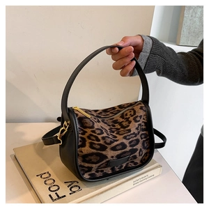 Detail of leopard print crossbody bag with black leather handles and gold metal zipper