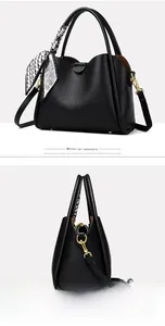 Detail view of black litchi texture handbag with printed silk scarf and gold hardware