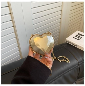Close-up of champagne gold heart-shaped acrylic clutch with diamond cut texture and chain