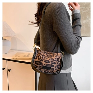 Close-up of the leopard print saddle bag with premium black leather trim and gold hardware