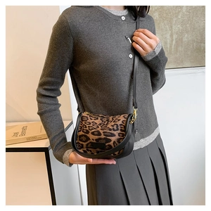 Detail of trendy leopard print crescent bag with adjustable strap and gold hardware