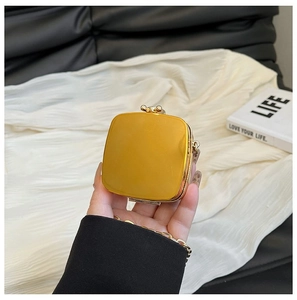 Close-up of golden metallic mini box bag with retro spherical clasp and chain