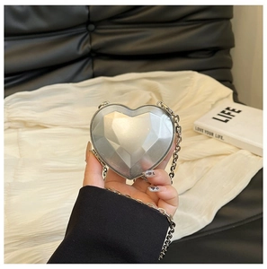 Detail of silver heart-shaped acrylic bag with diamond-cut facets and metal chain